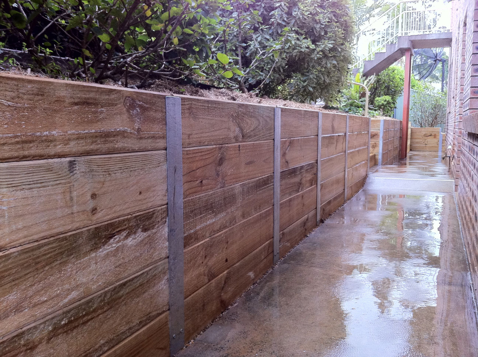 Completed timber sleeper retaining wall with steel posts and backfilled garden area